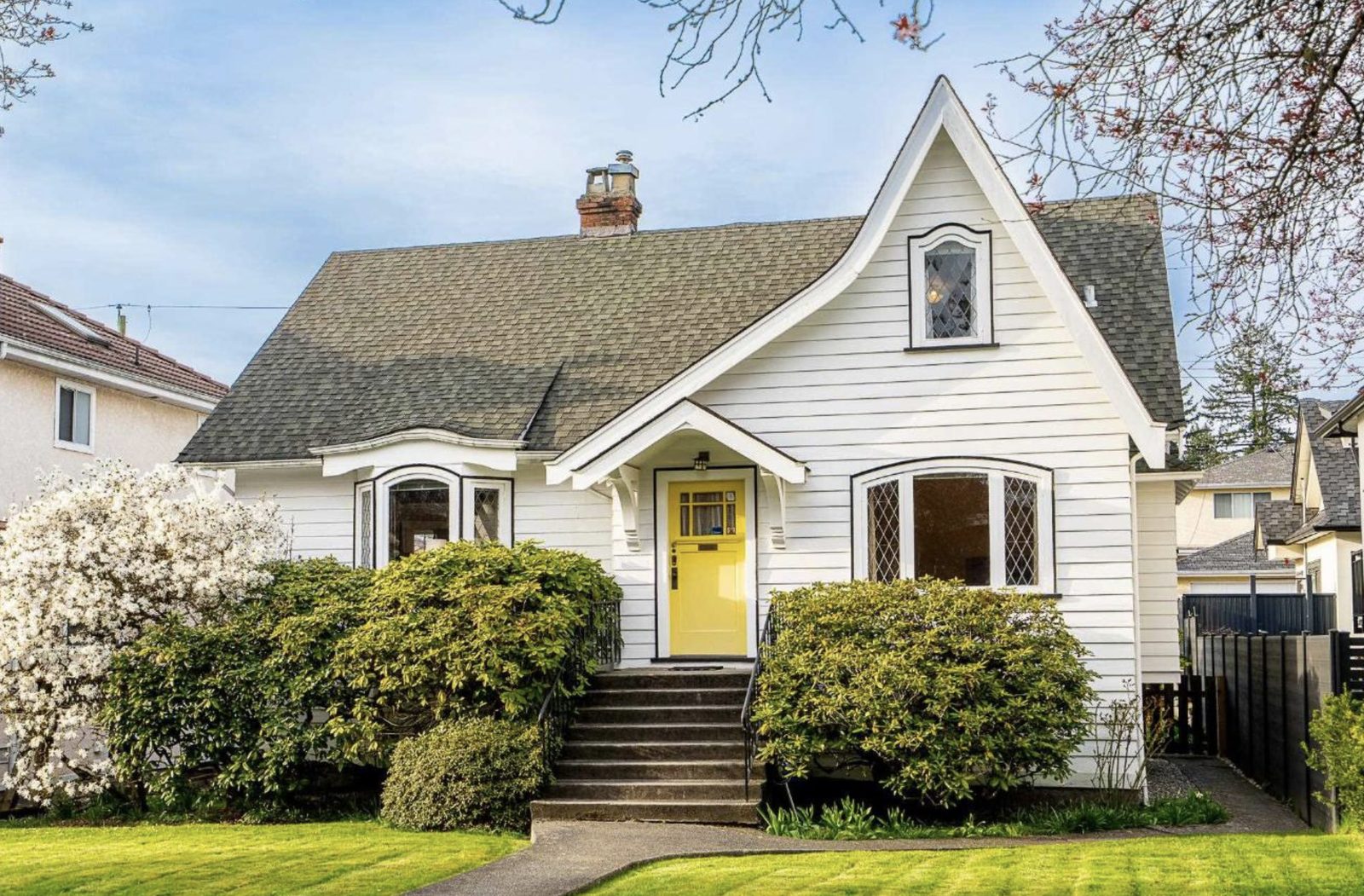 White heritage cottage with leaded windows and a yellow front door