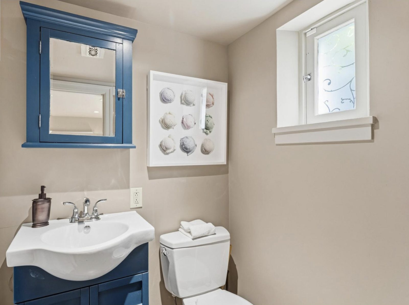 Bathroom with soft beige walls and a blue painted vanity and mirror cabinet